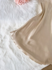 Gros plan sur l'ourlet de la nuisette en satin champagne avec dentelle délicate
