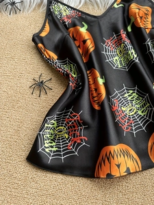 Detail of Halloween satin sleepwear with pumpkin and spider web prints on black fabric