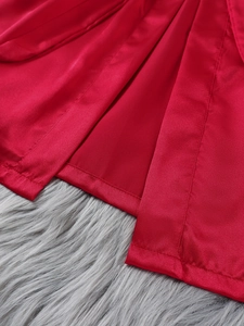 Detail of red satin robe showing fine stitching and smooth fabric texture on plush background
