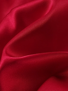 Close-up of luxurious red satin fabric with elegant silk luster and fine diagonal weave