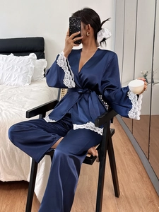 Detail of dark blue satin pajama set with white lace trim in a cozy bedroom setting