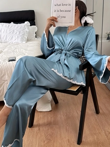 Close-up of blue-grey silk satin pajama set featuring white lace trim and v-neck tie design
