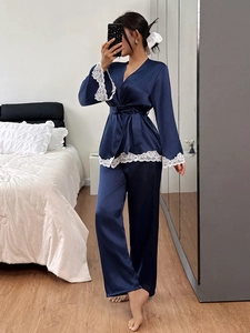 Detailed view of dark blue satin pajamas with white lace trim and wrap tie waist