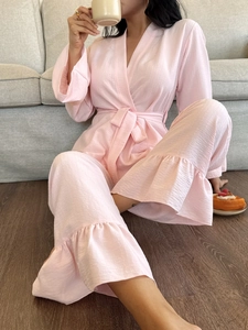 Detail of pink crepe fabric pajamas set featuring ruffled hems and wrap top design