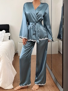 Detailed view of dark blue satin pajamas with white lace trim on cuffs and hemline