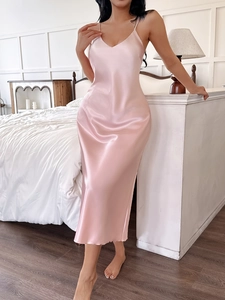 Detail of elegant pink satin slip dress with smooth texture and V-neckline in bedroom