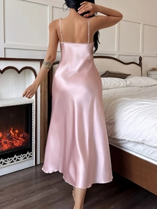 Close-up of pink satin slip dress featuring cross back straps and silky drape texture