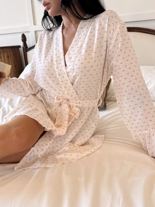 Detail of white cotton bathrobe featuring pink bow prints and ruffled sleeve cuffs
