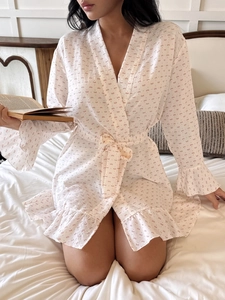 Detail of light beige cotton robe featuring floral bow patterns and ruffled hemline