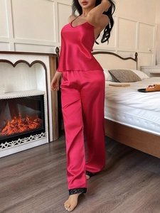 Detail of satin pajama set featuring delicate black lace trim on the hem of pink trousers