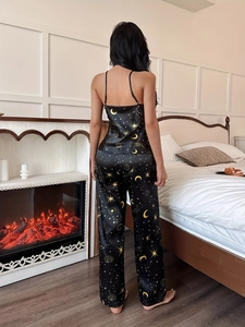 Detail of silk satin pajamas with gold celestial moon and star prints on black fabric