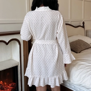 White cotton floral cloud bathrobe with ruffle hem and waist tie in cozy bedroom setting
