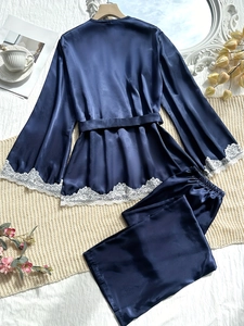 Close-up of navy silk pajama set with intricate white lace cuffs on textured bedding