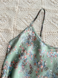 Close-up of floral satin nightgown fabric with smooth texture and delicate straps