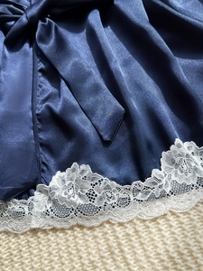 Detailed view of navy blue satin robe featuring intricate white floral lace trim and belt