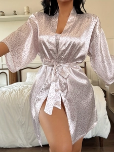 Detail of pink polka dot satin robe featuring smooth silk texture and waist tie closure