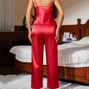 Red satin lace pajamas set with camisole and pants shown in a cozy bedroom setting