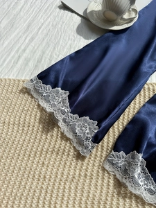 Close-up of luxury navy satin robe featuring exquisite white floral lace sleeve detailing