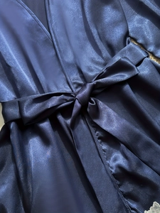 Detail of dark blue satin robe showing smooth fabric texture and matching waist tie bow