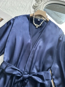 Detail of navy blue satin robe showing V-neck design, silk texture, and waist tie bow