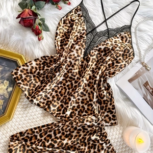 Silk leopard print pajama set with black lace trim and cross straps on white rug