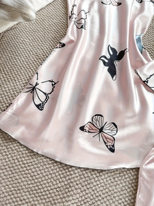 Vue détaillée du pyjama en satin rose avec imprimé papillon noir et coutures de précision