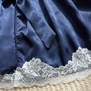 Navy blue satin robe with delicate white floral lace trim on soft plush background