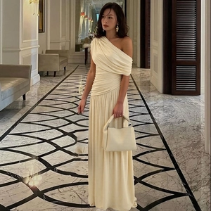 Detail eines cremefarbenen One-Shoulder-Kleides mit Faltenwurf und eleganter Silhouette