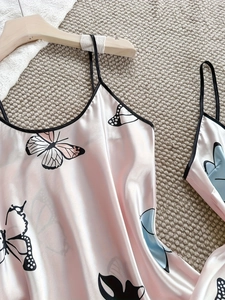 Détail du caraco en satin rose avec imprimés papillons géants et finitions noires
