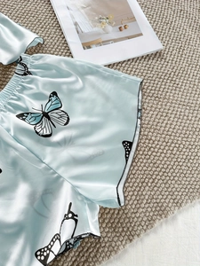 Gros plan sur un short de nuit en satin bleu clair avec imprimés papillons et taille élastique