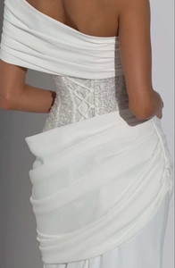Détail de la robe blanche à une épaule avec corset perlé et élégant tissu en satin drapé