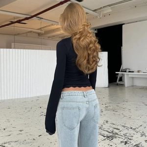 Vista posteriore del top nero aderente con bordo in pizzo e jeans azzurro chiaro