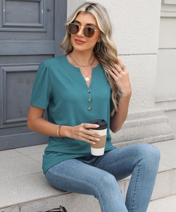Close-up of V-neckline with decorative buttons and pleated short sleeves on teal knit top