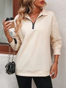 Close-up of beige half-zip sweatshirt featuring ribbed cuffs and metal zipper detail