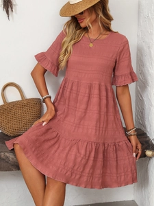 Detail of pink summer dress featuring ruffled short sleeves and tiered cake-style skirt