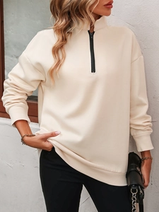 Detail of cream half-zip fleece sweatshirt featuring contrast black zipper and ribbed cuffs