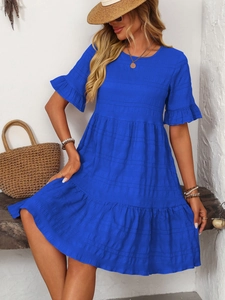 Detail of royal blue pleated dress featuring tiered skirt and ruffled short sleeves