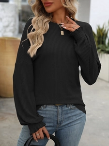 Detail of black ribbed knit shirt featuring elegant ruffled cuffs and elastic fabric texture