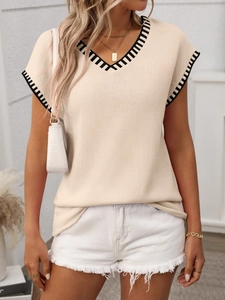 Detail of V-neck apricot knit vest with contrast black and white striped trim on neckline