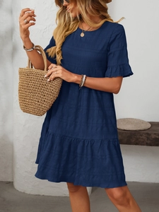 Detail of navy blue tiered dress showing textured seersucker fabric and smocked details