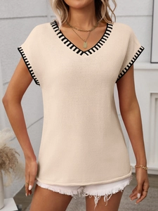 Detail of V-neck beige knit sweater vest with black and white striped ribbed trim