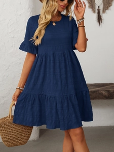 Detailed texture of navy blue pleated fabric on a tiered summer boho dress with short sleeves