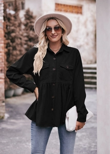 Detail of black corduroy babydoll shirt showing peplum hem and chest pockets in a street view