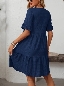 Detail of smocked texture and tiered hem on dark blue summer dress with short sleeves