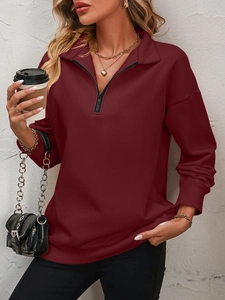 Detail of dark red half-zip fleece sweatshirt showing ribbed cuffs and metal zipper