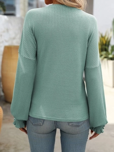 Detailed back view of a ribbed knit long sleeve top in sage green with ruffle cuffs