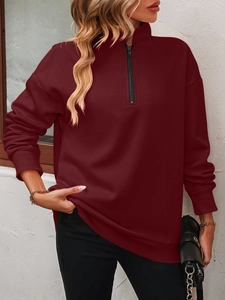 Detail of deep red half-zip sweatshirt showing fabric texture and ribbed cuffs