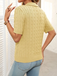 Close-up of the textured cable-knit pattern on the yellow short-sleeved polo sweater