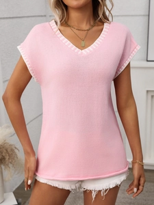 Detail of pink knit vest with V-neckline and contrasting white striped ribbed trim