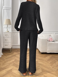 Detail of black ribbed knit loungewear set featuring a crew neck top and wide-leg trousers
